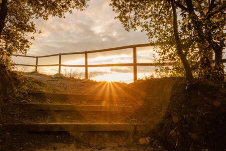 stairway guides to a golden sunrise above a wooden fence surrounded by trees in Crossa Volcano near to Sant Dalmai in Gironaの写真素材