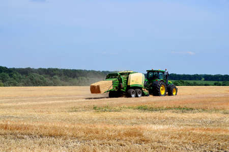 Kharkiv / Ukraine - June 27, 2019: Agricultural field of ripe sowing of rye, the harvester collects a rich crop of cereals.のeditorial素材