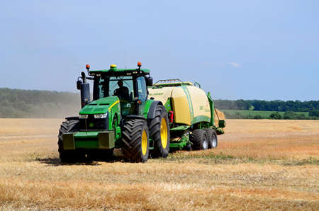 Kharkiv / Ukraine - June 27, 2019: Agricultural field of ripe sowing of rye, the harvester collects a rich crop of cereals.のeditorial素材