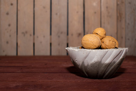 walnuts in a concrete cup and place for text. wooden background. horizontal view