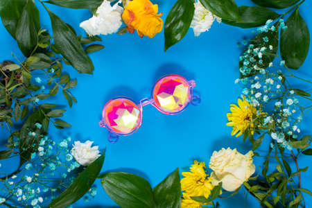 Round frame made of yellow and white summer flowers with green leaves. in the center are glasses kaleidoscopeの写真素材
