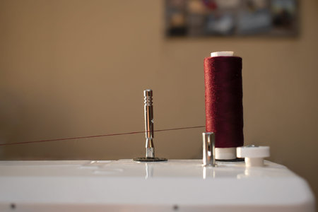 thread spool on a sewing machine close-up on the brown backgound