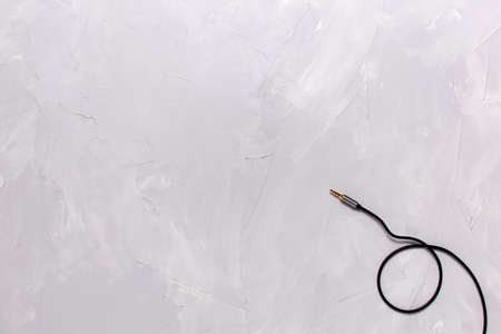 Metal gold plug on a black audio instrument cable, on a plastered background close-up from right to left. Flat lay. Copy Space.の写真素材