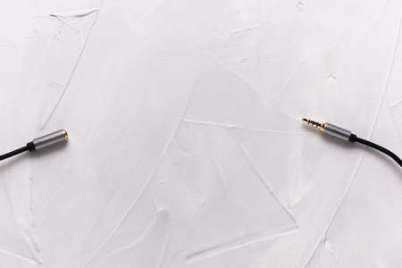 Metal gold plug on a black audio instrument cable, on a plastered background close-up from right to left. Copy Space. View from above.の写真素材