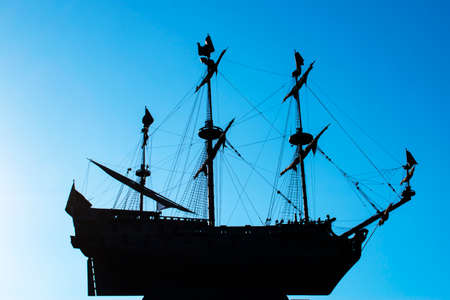 Silhouette of a frigate on a blue clear sky. Three-masted sailing ship soaring in the air.の写真素材