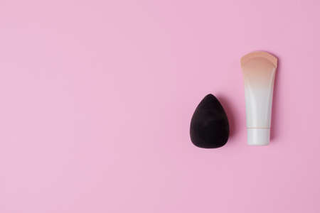 Cosmetics and accessories on a pink background. flat lay. Black face sponge for cosmetics and foundation on a pink pastel backgroundの写真素材