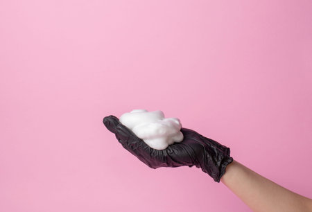 The stylist's hand in a black glove holds a hairbrush. the second hand takes the foam. hair care...