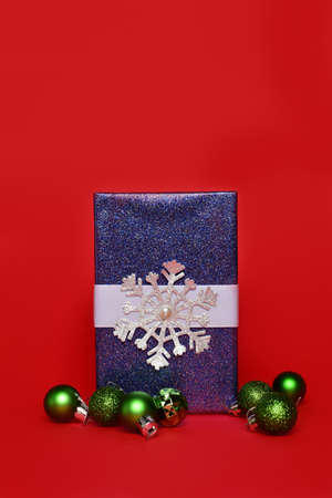 Blue gift on a red background. Around the gift are scattered small New Year's Christmas toys. New Year concept, copy space.の写真素材