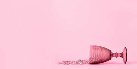 a pink glass and beads lie against a pastel pink background. Minimalism. Copy space.の写真素材