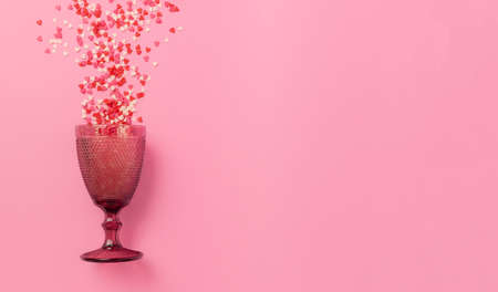 the pink glass capsized and small sweet hearts of different colors scattered from pastel pink background. The concept of bright and happy emotions. Minimalism. Copy space.の写真素材