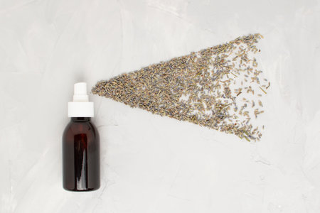 Transparent cosmetic amber glass spray bottle on a white background. Lavender flowers scatter like...