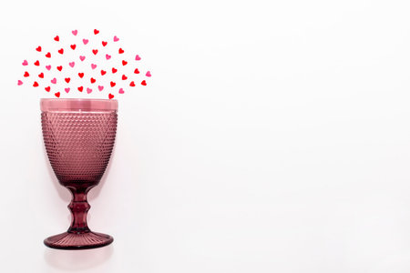 small sweet hearts lie in a semicircle over a pink glass on a white background. horizontal photo. Flat lay. Copy space