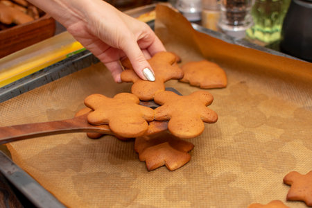 Christmas hot cookies are collected with a small wooden spatula from a baking sheet. Warm light,...