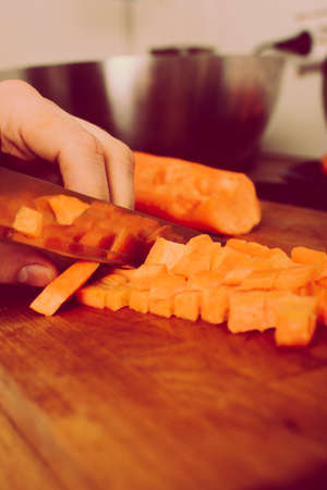 man cutting vegetables on wooden board. onion , carrot , paprika. retro vintage styleの写真素材