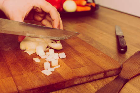 man cutting vegetables on wooden board. onion , carrot , paprika. retro vintage styleの写真素材