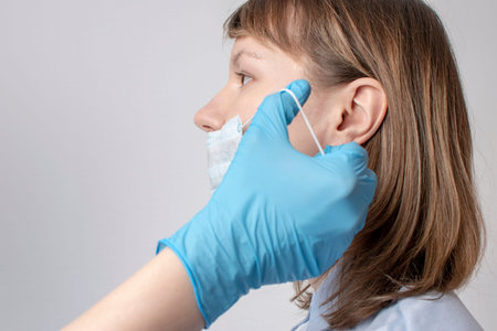 mans hands puts a protective mask on woman mouth.