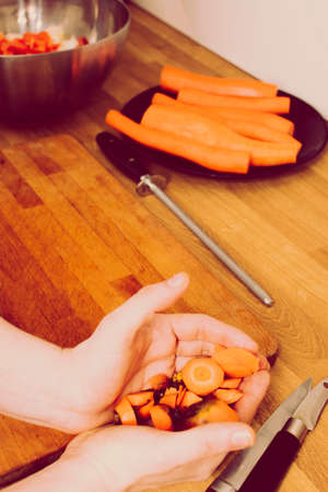 man's hands collect carrot leftovers from wooden board. old, vintage, retro styleの写真素材