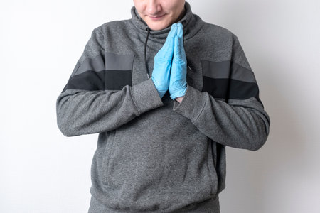Caucasian man in blue gloves on an isolated background smiles and holds palms togetherの写真素材