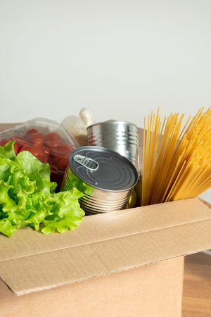 Box filled with food on an isolated background. In the box are vegetables, fruits, bananas, carrots, eggs, fresh salad, spaghetti, canned foods. Concept of donation, home delivery foodの写真素材