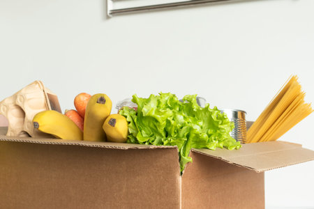 Box filled with food on an isolated background. In the box are vegetables, fruits, bananas, carrots,...