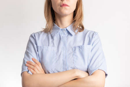 serious business woman in a blue shirt with crossed arms on a white backgroundの写真素材