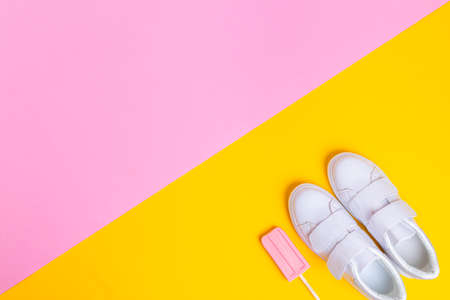 White sneakers and pink ice cream on a yellow pink background in the corner of the frame. View from above. Bright summertime conceptの写真素材