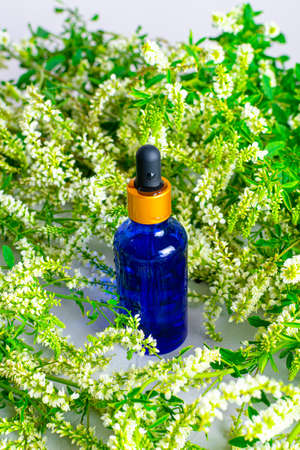 A glass dropper bottle blue on a scattering of fragrant wildflowers. Natural cosmetic and skincare. Aroma essential oilの写真素材