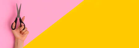Scissors are in the woman's left hand. Banner in bright pink and yellow, split in half. International Left-handers Day on August 13の写真素材