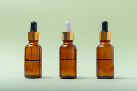 Mock up glass cosmetic brown bottles with a pipette on a mint backgroundの写真素材