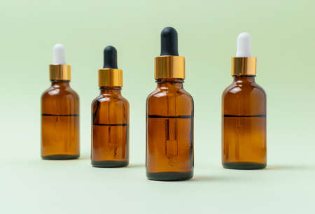 Mock up glass cosmetic brown bottles with a pipette on a mint backgroundの写真素材