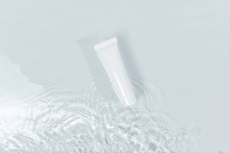 White tube in water. Beautiful stains on the water. Mockup of cosmetic products