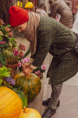 A young woman chooses a pumpkin for a holiday at a grocery storeの写真素材