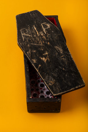 A miniature homemade red and black coffin on a yellow background, from which many plastic eyes pop...