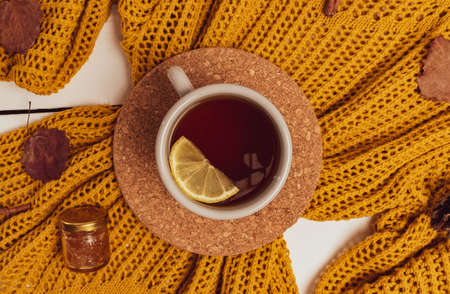 Cozy flat lay of lemon tea cup, yellow sweater, leaves, cinnamon sticks and pine cones. Autumn compositionの写真素材