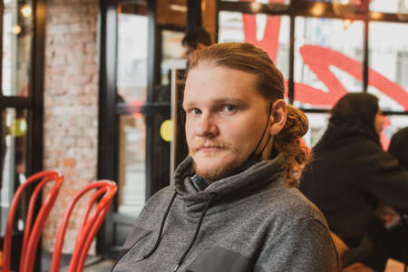 Portrait of a young man in a cafe with a mask on his chinの写真素材
