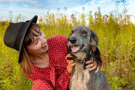 Young happy woman plays with her purebred gray dog in the parkの写真素材