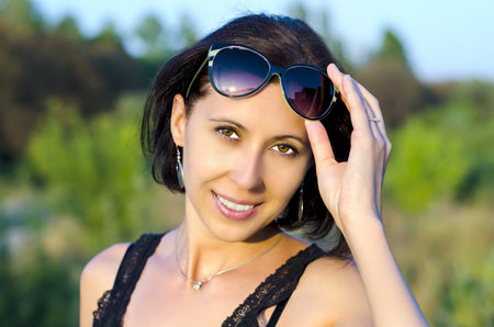 A beautiful woman smiles with sunglasses push up on top of her head.