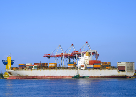 Cargo ship in industrial docks and reflections in the waterの写真素材