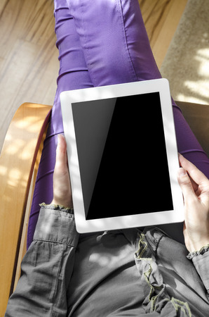 Woman holding a tablet computer sitting in a chairの写真素材