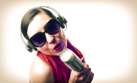 Beautiful girl in the red with microphone. Vintage photoの写真素材