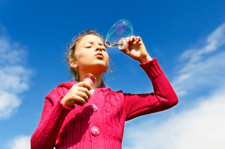 Portrait of funny little girl  blowing soap bubbles