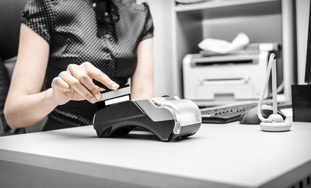 Female hand holding plastic card in bank terminalの写真素材