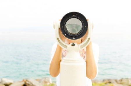 Woman looking through binoculars or telescopeの写真素材