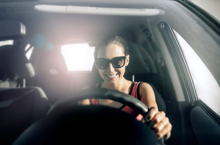 Woman drives a car in the rays of bright light