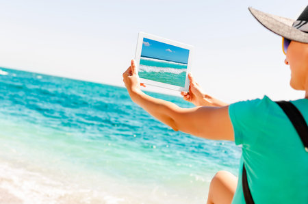 Girl photographs waves of the sea on a sunny day