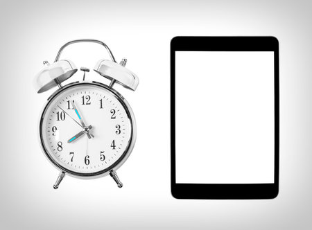 Tablet computer and alarm clock. Time and technology. Concept.