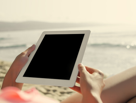girl looking at tablet pc on the beachの写真素材