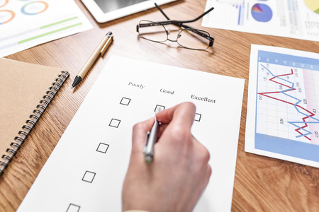 Examination paper on the office desk. Hand marks the estimate.の写真素材