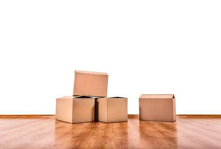 Moving boxes on the floor of an empty room with a white wall.