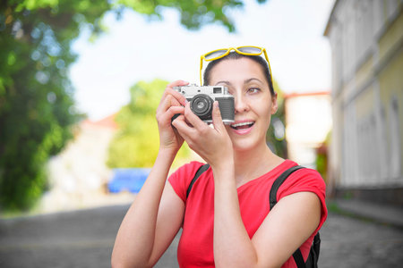 Tourist girl using camera to take photograph on travel. Focus on camera.